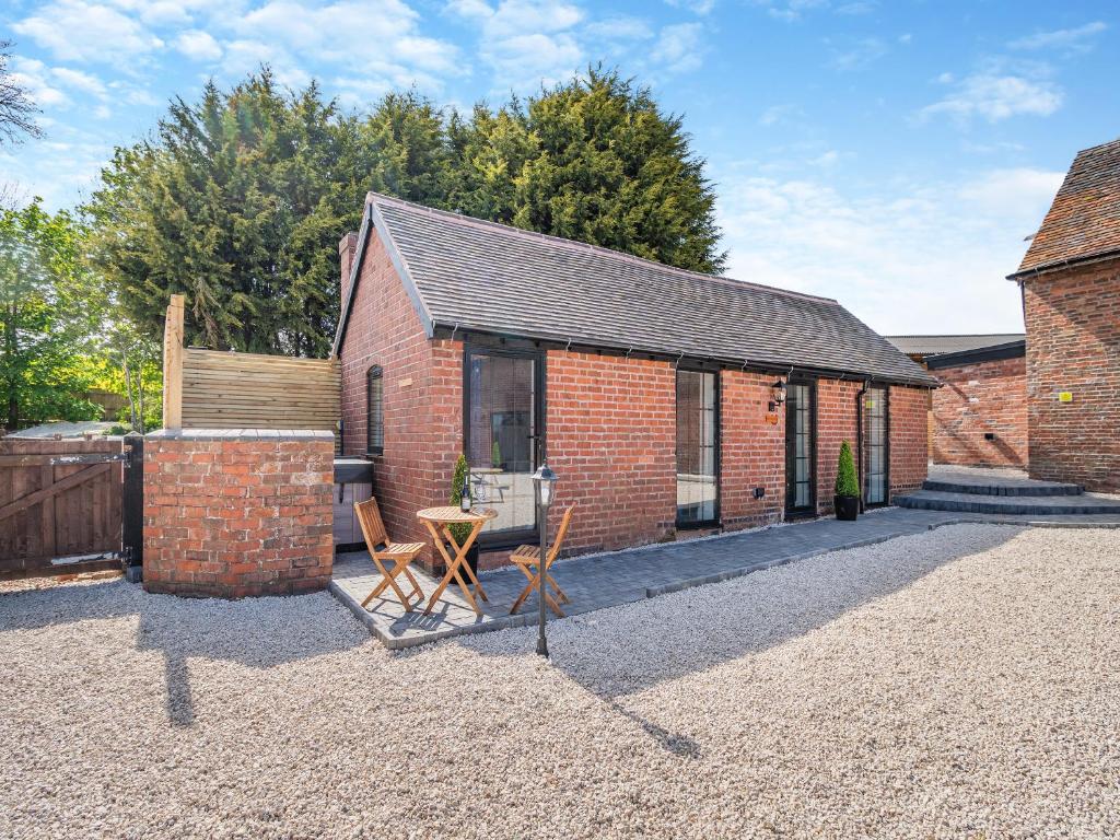 een bakstenen huis met twee stoelen op de binnenplaats bij Fountain Front Barn - Uk45937 in Corley