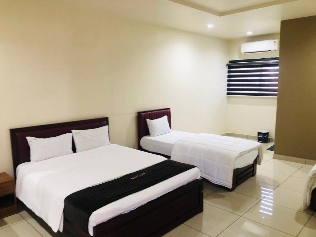 CalicutAtland Residency的酒店房间有两张床，床单是白色的