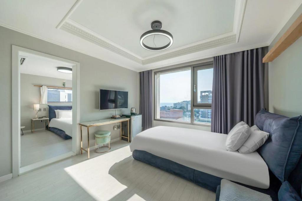 een hotelkamer met een bed en een groot raam bij Cornerstone Hotel in Seogwipo