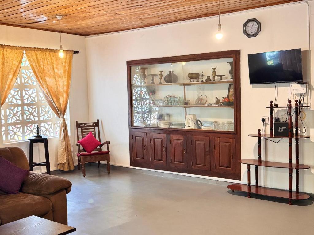 a living room with a wooden cabinet and a tv at Wave Loom Hostel Ahangama in Ahangama