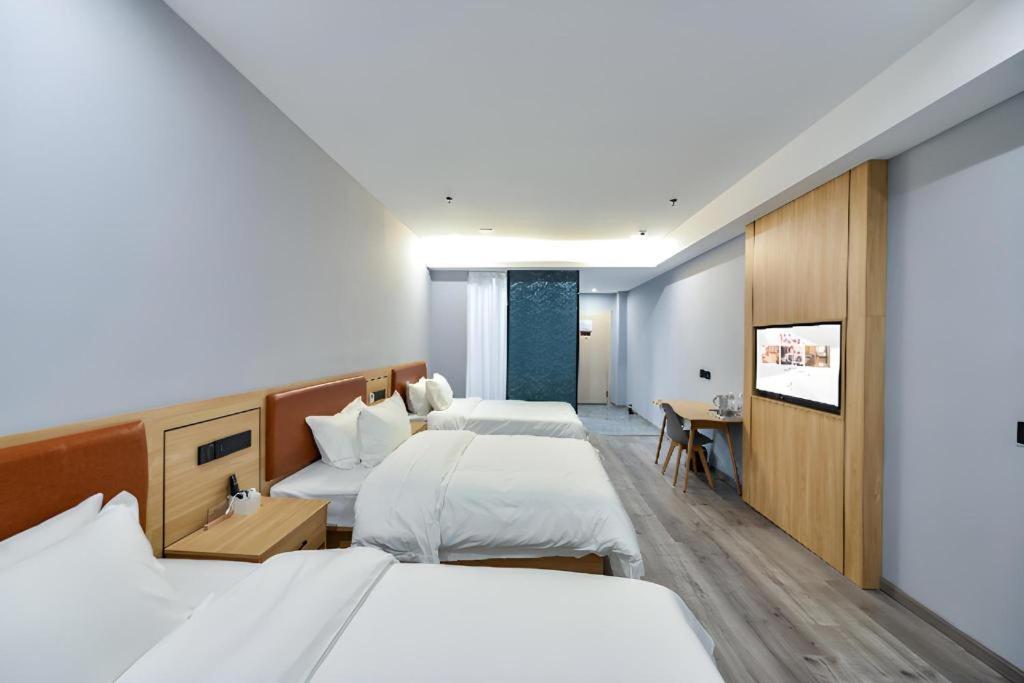 een hotelkamer met twee bedden en een televisie bij Borrman Hotel Jiangyin Zhouzhuang in Xiwujieqiao