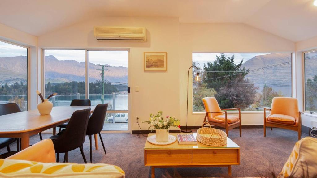 a living room with a table and chairs and windows at Ruru Retreat- Free Parking- Hot Tub- Walk To Town in Queenstown