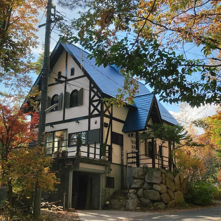 a large white house with a blue roof at Forest View Guesthouse in Omachi