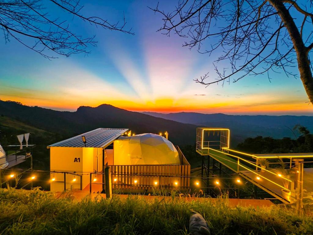 a view of a large building with the sunset in the background at เอวาเเคมป์ ภูชี้ฟ้า Avacamp phuchifa in Ban Seng Choi