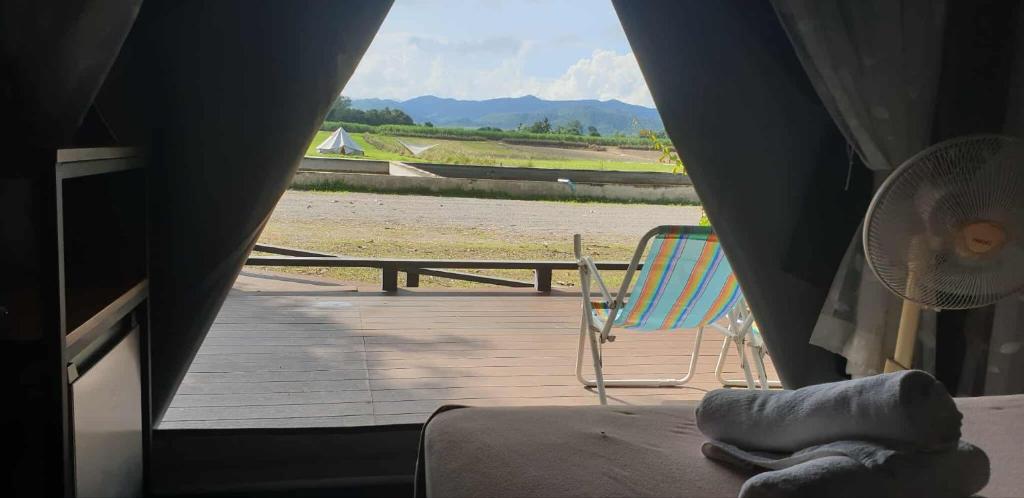 a room with a deck with a chair and a fan at The Camping Field in Ban Kluai