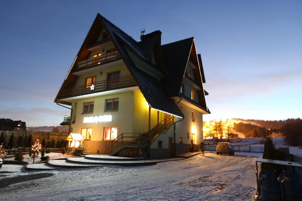a large house in the snow at dusk at Małgosia - 10 minut na piechotę do stoku narciarskiego i basenów termalnych Bania - atrakcyjny pakiet wielkanocny in Białka Tatrzanska