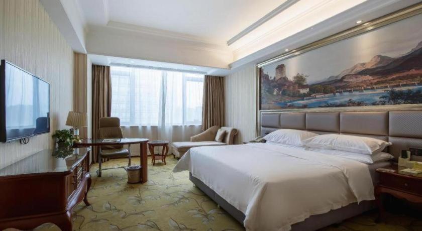 a hotel room with a large bed and a television at Vienna International Shanghai Nanxiang in Chenjiahang
