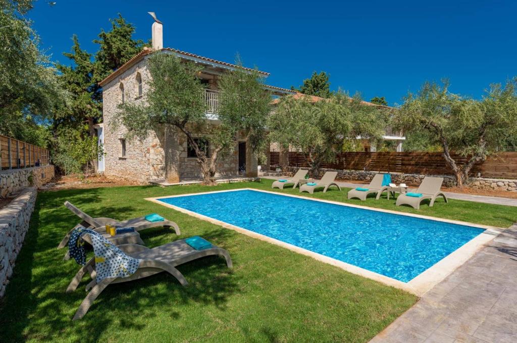 een achtertuin met een zwembad en een huis bij Villa Ionio Elia by Villa Plus in Vasilikos