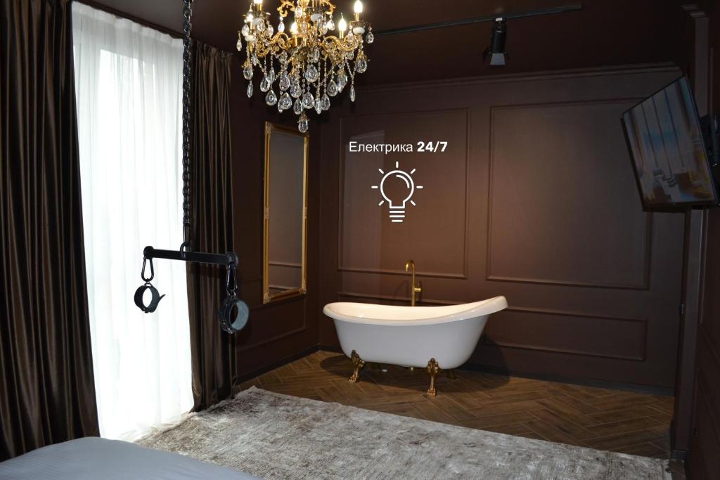 a bathroom with a bath tub and a chandelier at Park Gate apartment in Chernivtsi