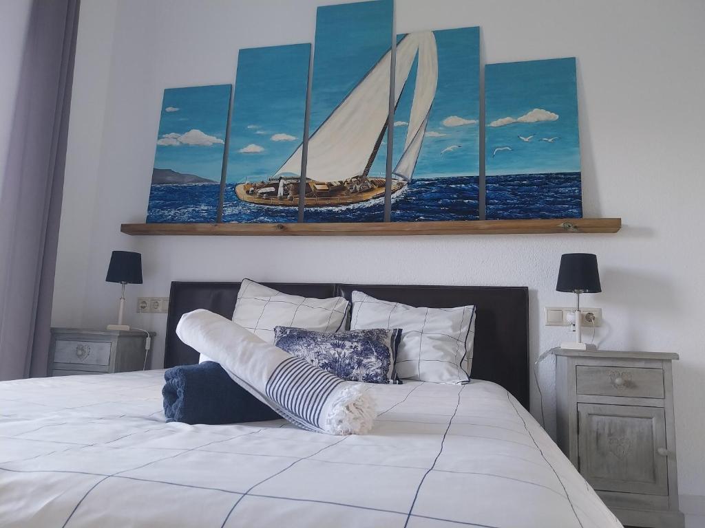a bedroom with a bed with a painting of a sailboat at La casa del mar Nuimna in Peñíscola