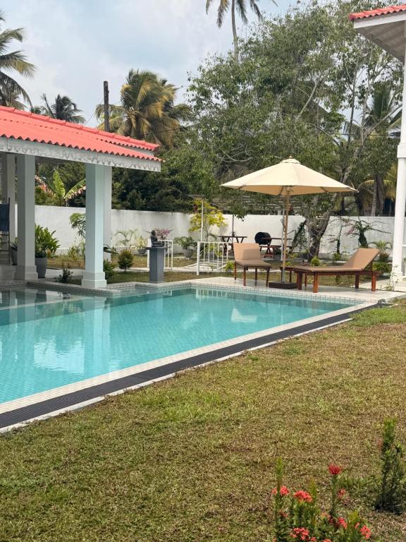a swimming pool with a table and an umbrella at Interlanka Coast Living in Ahangama