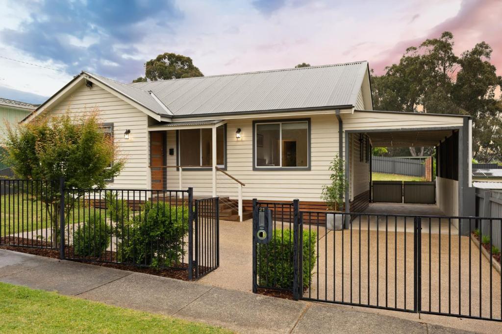 ein weißes Haus mit einem schwarzen Zaun in der Unterkunft Lemon & Myrtle Cottage in Myrtleford