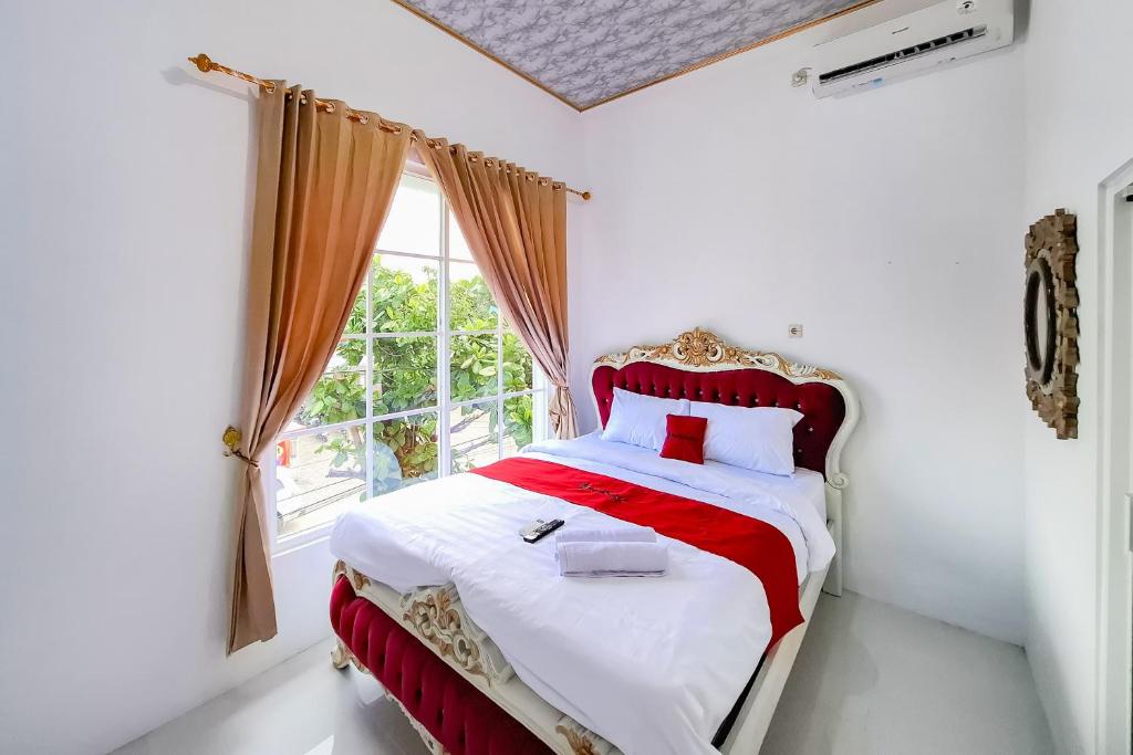 a bedroom with a red and white bed with a window at RedDoorz Syariah Near Kantor Bupati Jepara in Jepara