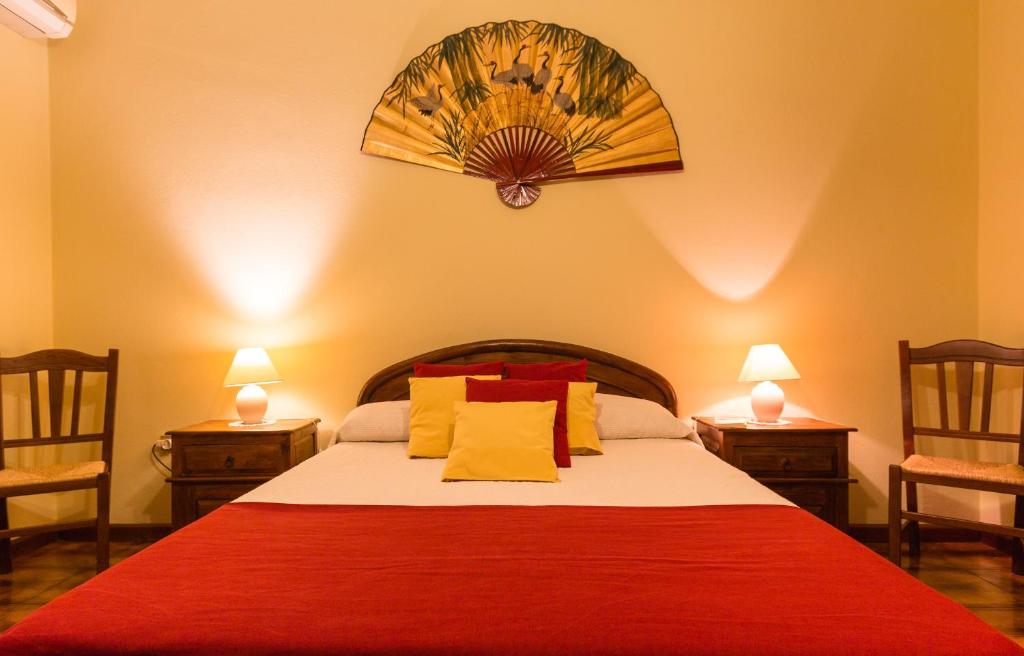 Schlafzimmer mit einem Bett mit roten und gelben Kissen in der Unterkunft Su Connotu in Sestu