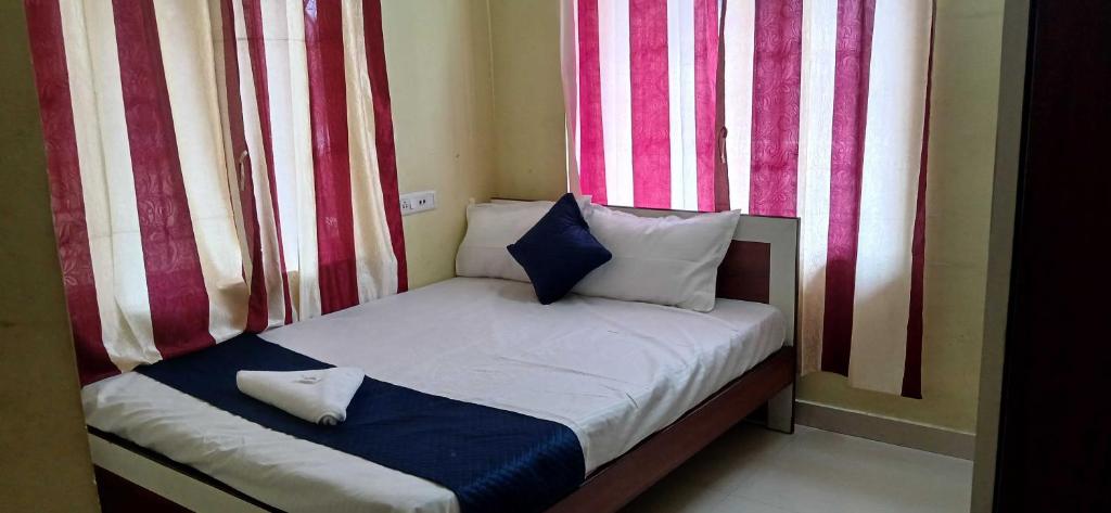 a small bed in a room with red and white curtains at Hotel O Sharan Guest House in Calcutta Bara Bazar