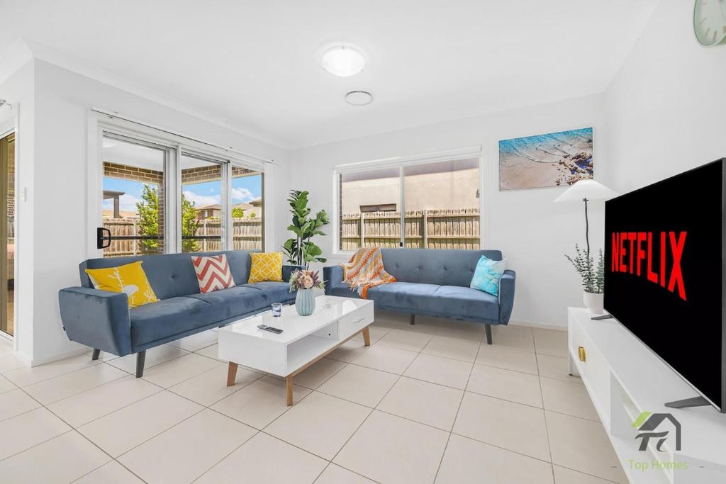 Una sala de estar con dos sofás azules y un televisor. en Five Bedrooms Near Schofields Station Direct Access to Sydney University & Parramatta, en Schofields