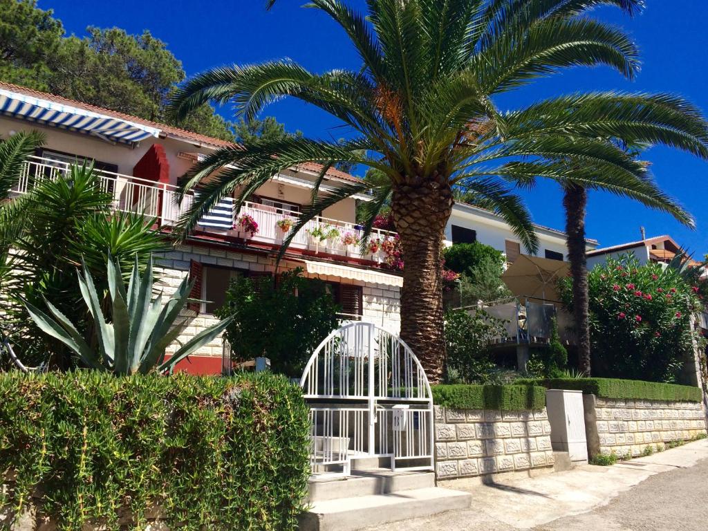 a palm tree in front of a building with a gate at Apartment Stella in Mali Lošinj