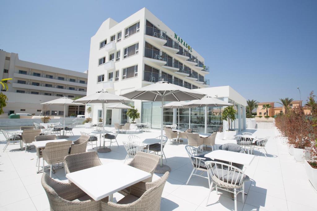 
a hotel room with tables and chairs and umbrellas at Napasol Boutique Hotel in Ayia Napa
