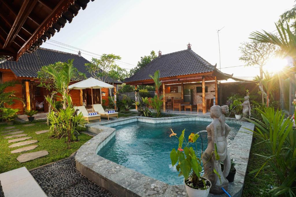 ein Pool mit einer Statue vor einem Haus in der Unterkunft Puri Bucuana Villa in Bedahulu