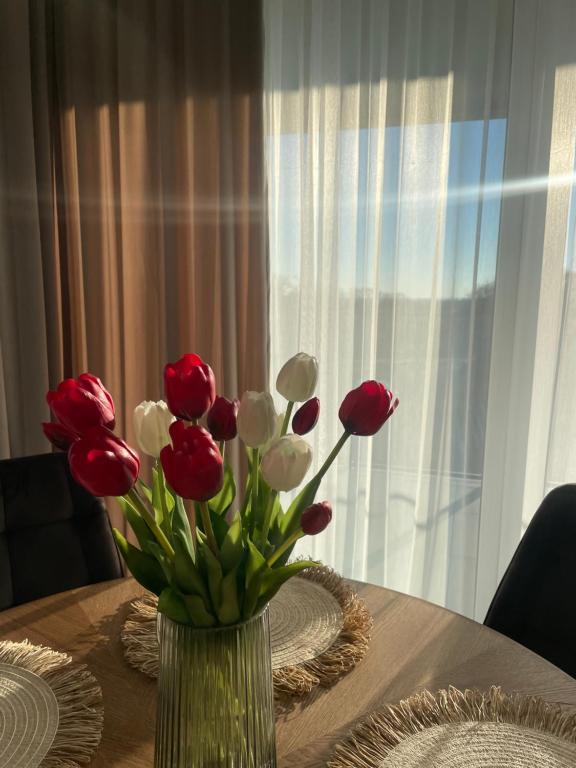 een vaas met rode en witte bloemen op een tafel bij Apartament HYGGE in Busko-Zdrój