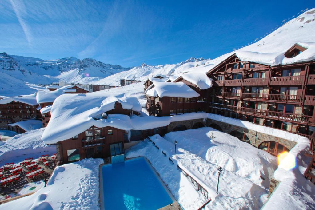 a snow covered ski slope with a large building at Hotel Village Montana by Les Etincelles in Tignes