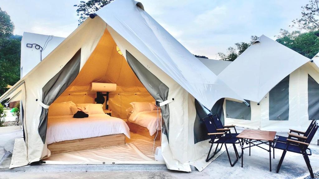 a tent with a bed and two chairs and a table at TheNyaman Place in Hulu Langat