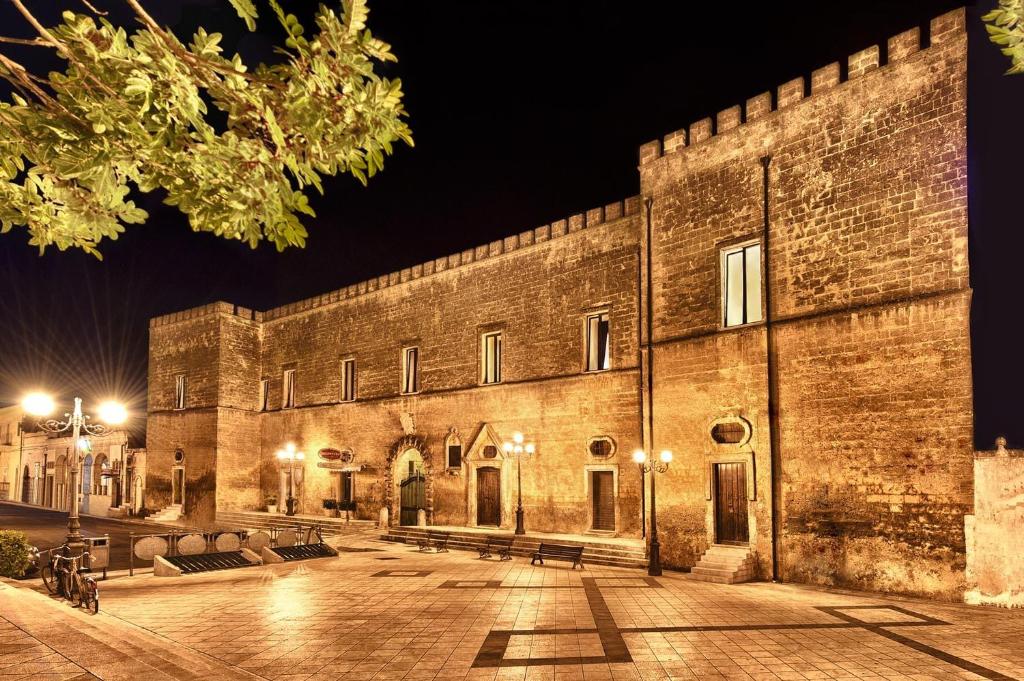 un gran edificio de ladrillo con bancos al aire libre por la noche en Castello Conti Filo en Torre Santa Susanna