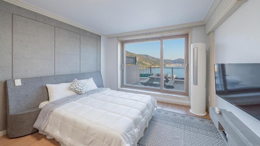 a bedroom with a large bed and a large window at Maremonte Pension in Geoje 