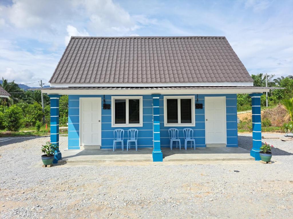 a blue house with chairs in front of it at Teratak Sumayyah 1 - For Islam only - Pondok Lenggong in Kampong Banggol Belimbing