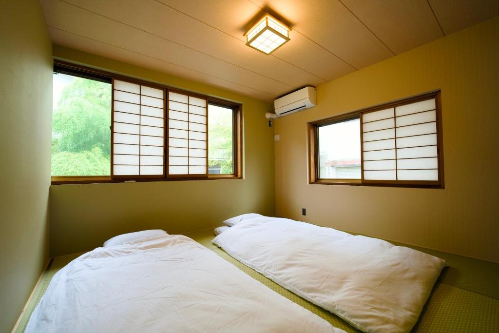 a bedroom with two beds and two windows at 康郷 箱根湯本 in Wada