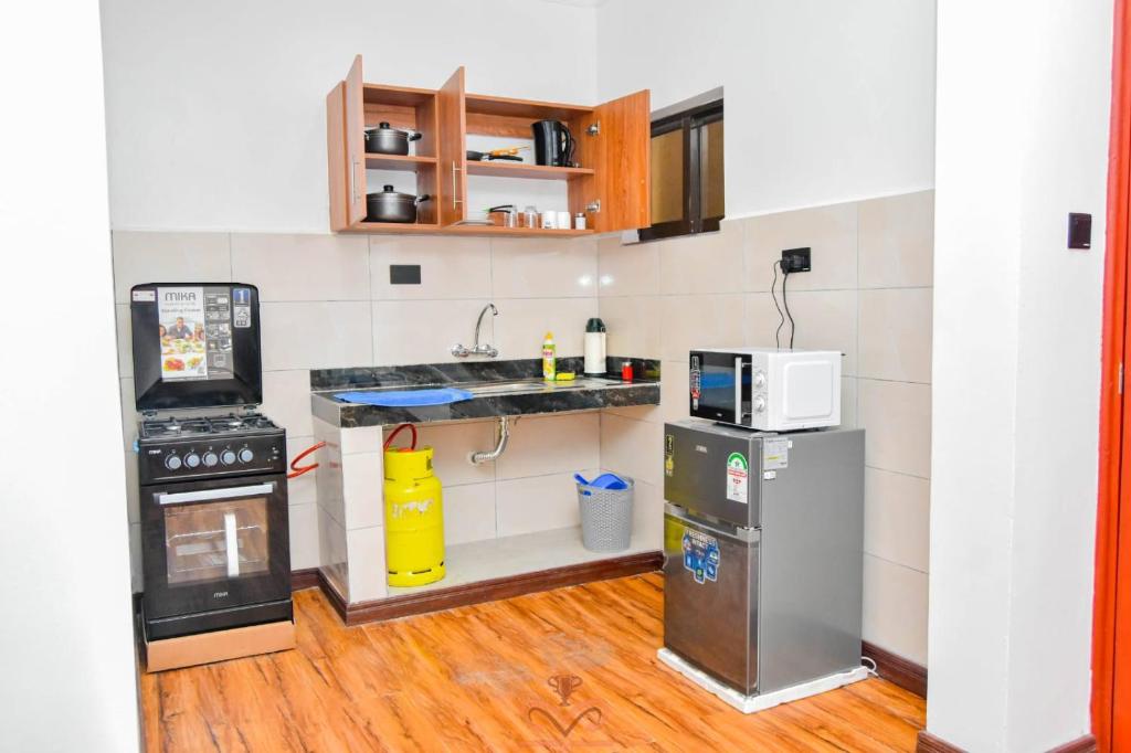 a small kitchen with a stove and a refrigerator at Monalisa Studio Apartments in Gatunga
