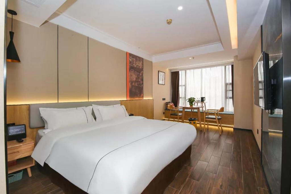 a large white bed in a room with a table at Chenlong Cafe Hotel in Guangzhou
