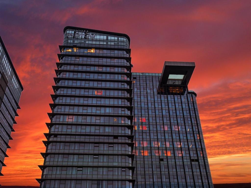 a tall building with a sunset in the background at Hotel Indigo Zhuhai Xiangzhou by IHG in Zhuhai