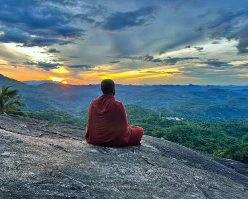 a man sitting on a rock watching the sunset at Ella Nature Park Hostel in Ella