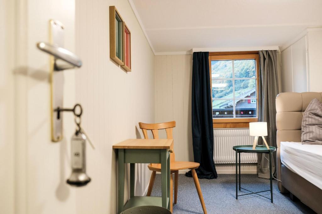 een kamer met een bed, een bureau en een raam bij DASCO Isenthal in Isenthal