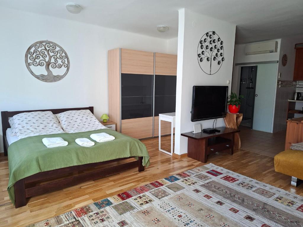 a bedroom with a bed and a flat screen tv at Centrum apartman in Szekszárd