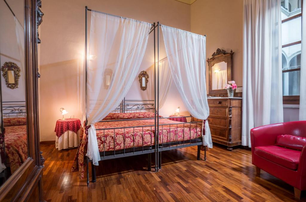 a bedroom with a canopy bed and a red couch at Hotel Torre Guelfa Palazzo Acciaiuoli in Florence