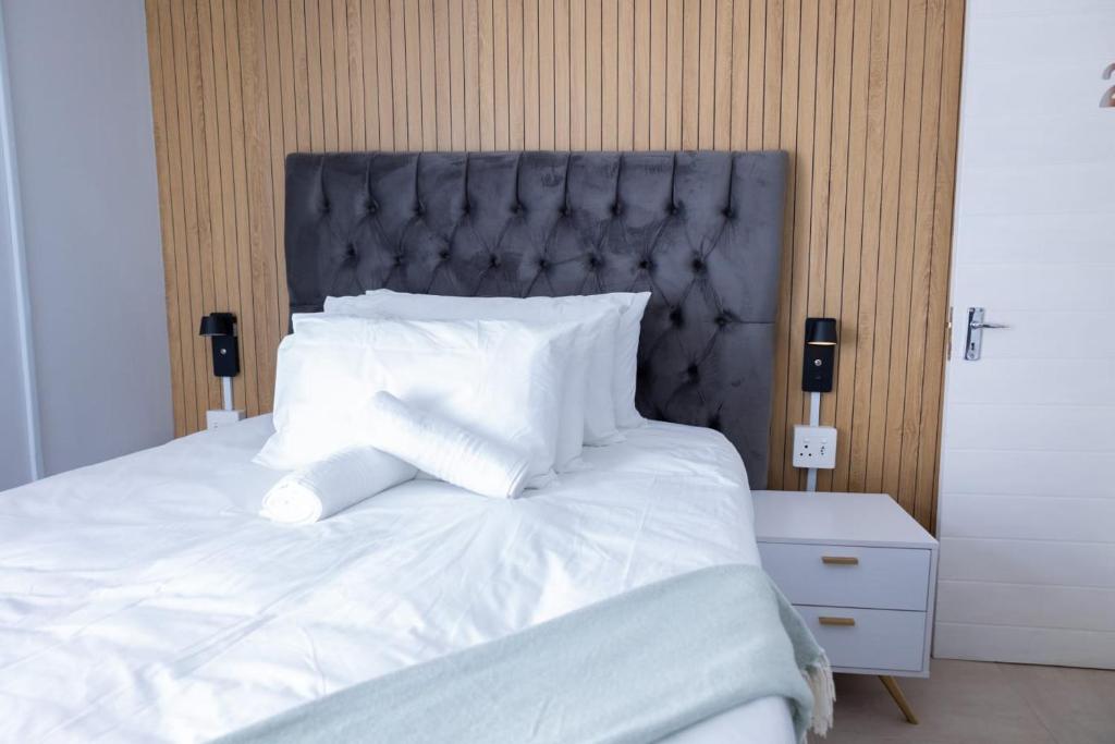 a large bed with white sheets and pillows at Towny Lodge in Kokstad