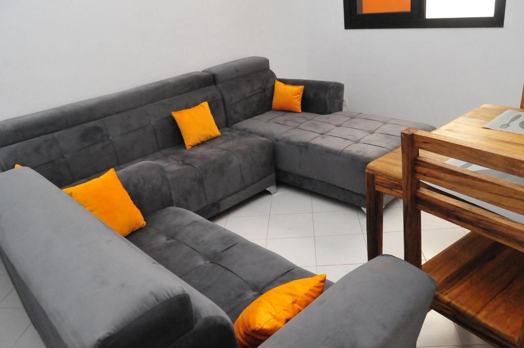 a living room with a gray couch with orange pillows at WHITE FLAT ALMADIES in Dakar
