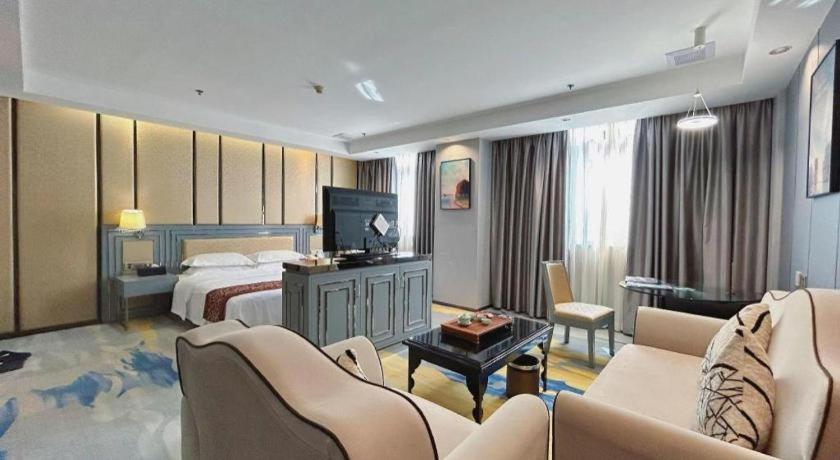 a bedroom with a bed and a living room at GreenTree Inn Shantou Chengjiang Road Business Hotel in Xialian