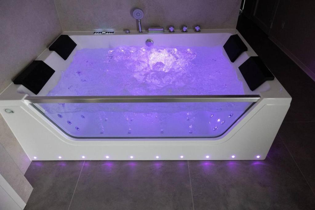 a purple bath tub with purple lighting in a bathroom at Maison MUGUET 2 SPA-PARKING-COLMAR in Wickerschwihr