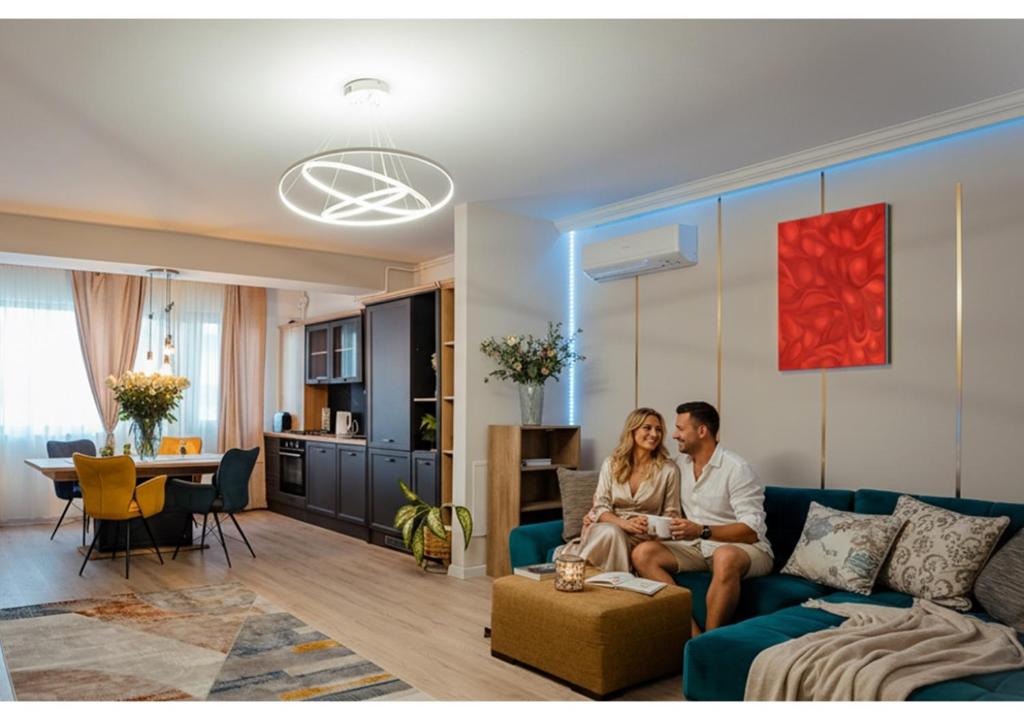 un hombre y una mujer sentados en un sofá en una sala de estar en Ivory Garden Retreat by Blvd 60B2 - Luxury Apartment in Voluntari, en Voluntari