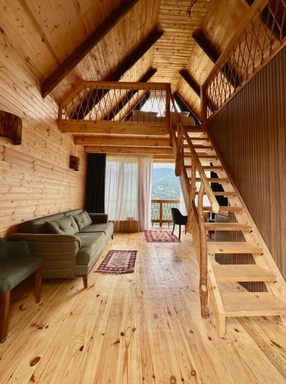 a living room with a couch and stairs in a cabin at Dreamy Garden Cabin in Gundauri