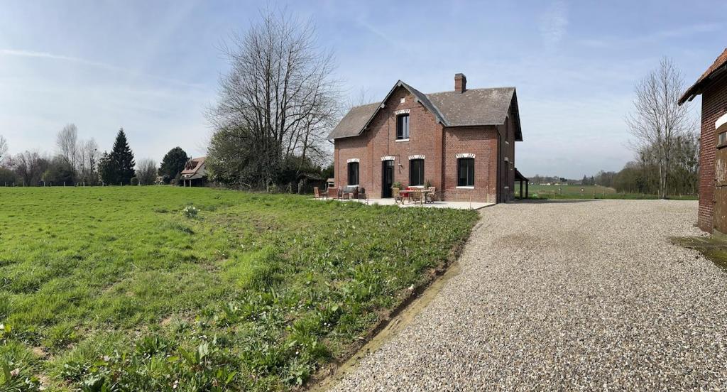 an old brick house in a field next to a building at Le Hameau Paisible in Butot