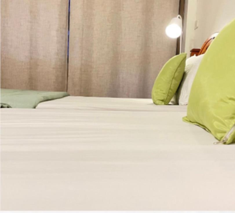 a bed with white sheets and green pillows at A Day Rayong in Ban Pa Khan