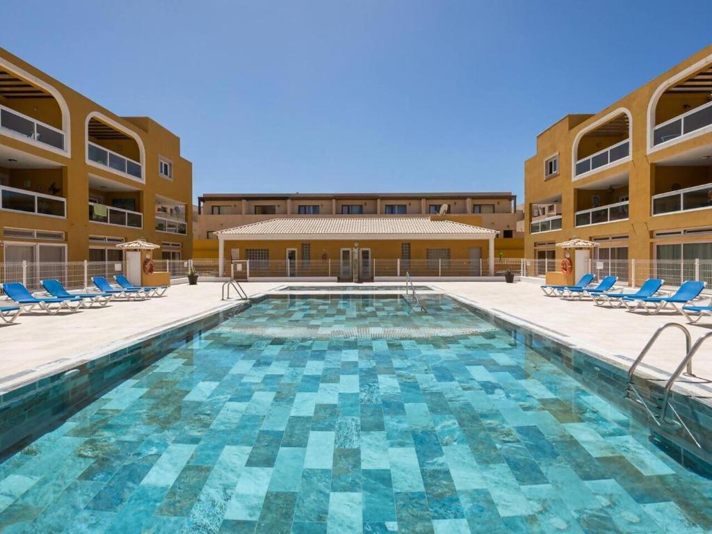a swimming pool with chairs and a building at My little paradise in Cotillo