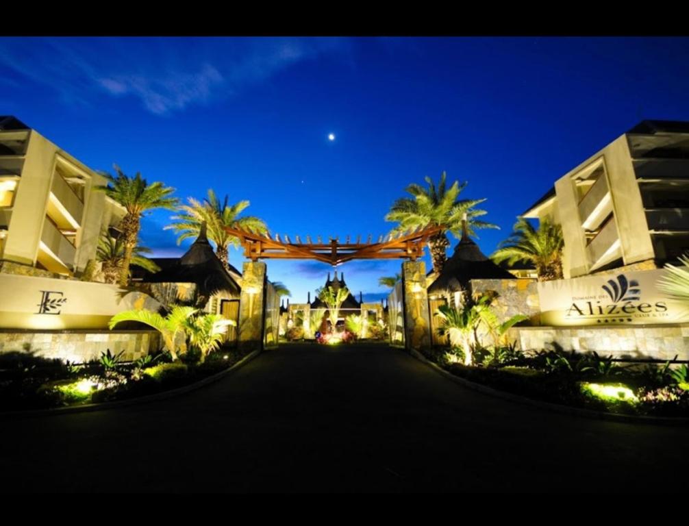 Domaine Des Alizees Residence في غراند بايَ: مدخل المنتجع في الليل مع أشجار النخيل