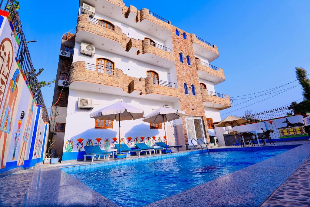 un hotel con piscina frente a un edificio en Sun wing guest house, en Luxor