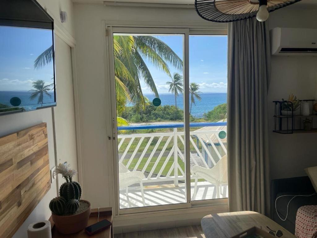 una camera con una grande porta scorrevole in vetro con vista sull'oceano di Mango Paradise a Saint-François