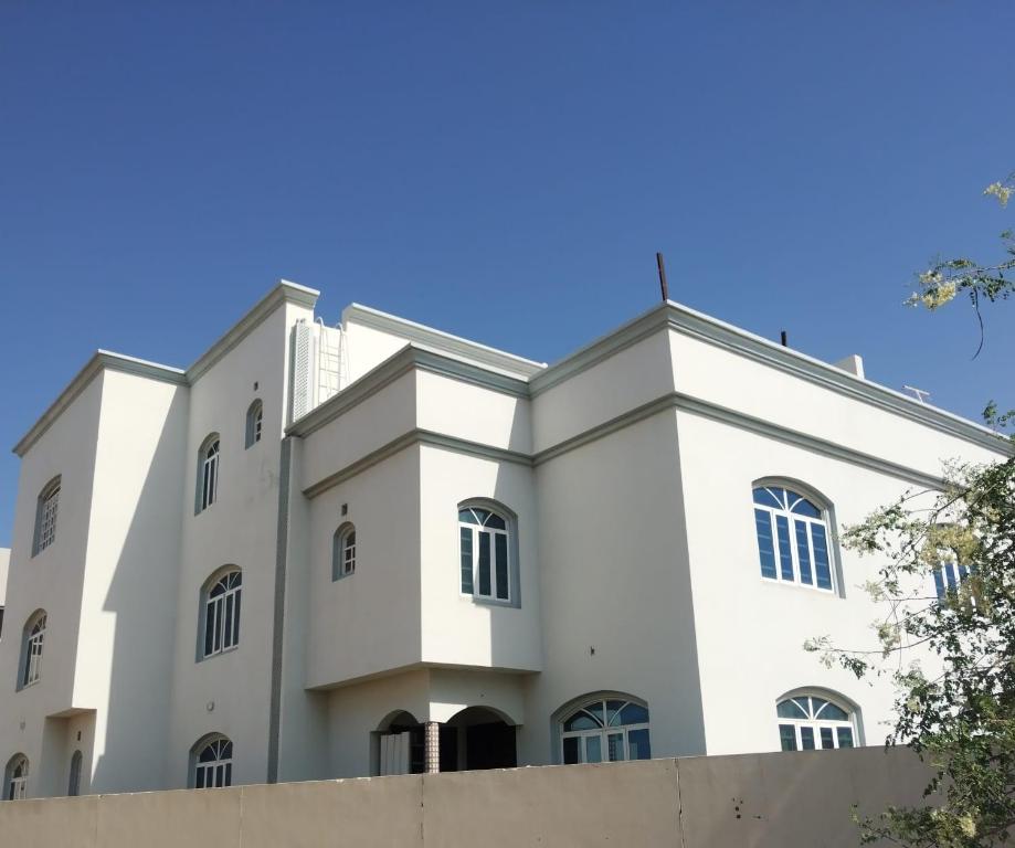 a white building with a blue sky in the background at Raha Hostel in Ḩayl Āl ‘Umayr